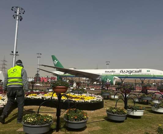 Flower beds and baskets with an aircraft display behind